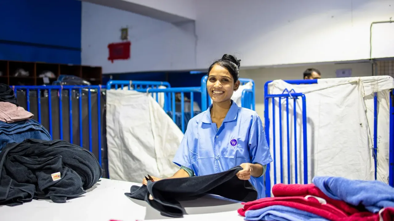 Streamlining Laundry: A System for People with Zero Free Time Funcionário de serviço de lavanderia dobrando roupas, sugerindo a opção de terceirizar a lavanderia para economizar tempo.