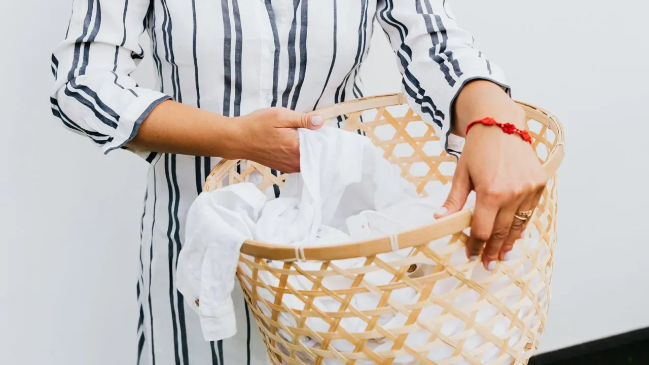 Streamlining Laundry: A System for People with Zero Free Time Três cestos de roupa suja etiquetados para pré-separação, ilustrando a economia de tempo ao reduzir decisões.